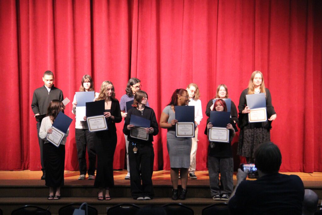 Students receiving their National Honor Society Induction certificates and signing the oath book at Parma Community NHS ceremony.