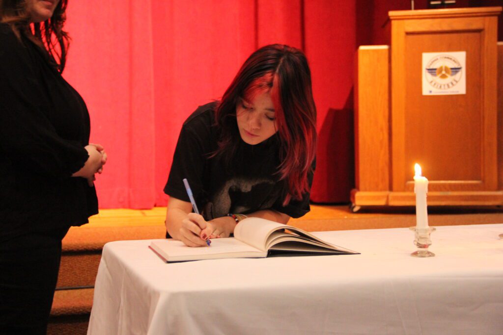 Students receiving their National Honor Society Induction certificates and signing the oath book at Parma Community NHS ceremony.